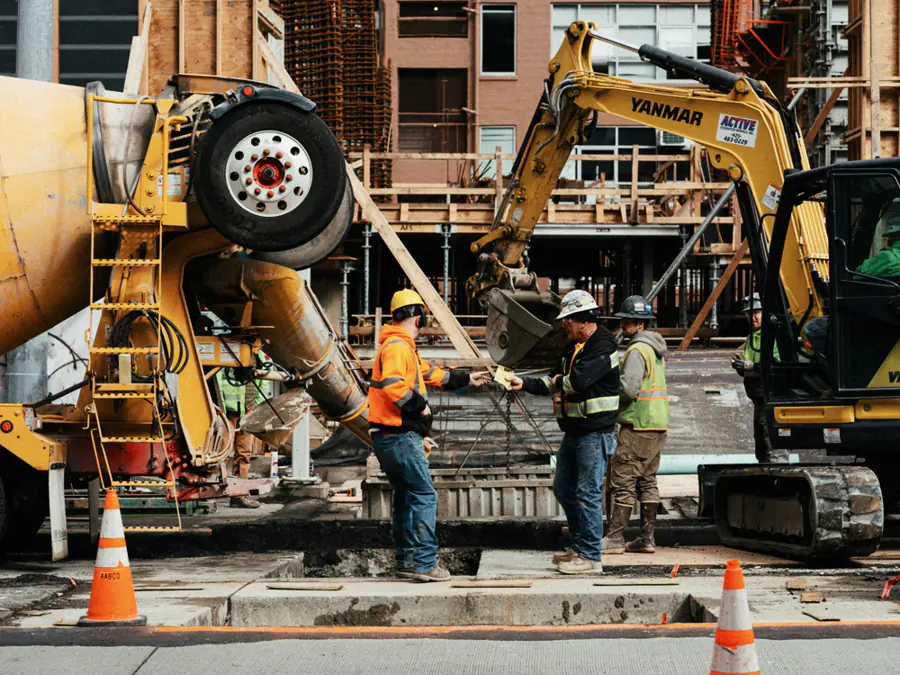 Betonstort met graafmachine en bouwvakkers