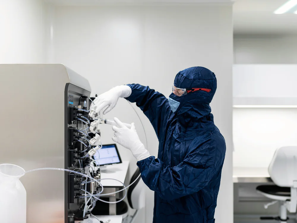 Medewerker in cleanroomkleding bedient een machine