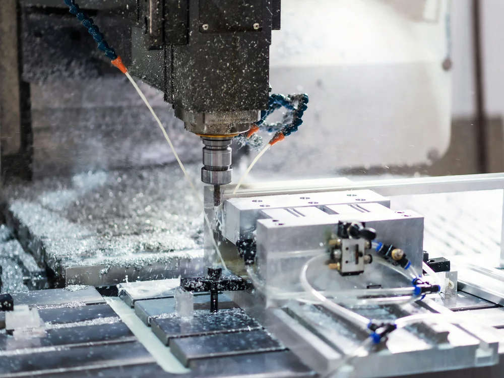 CNC-freesmachine bewerkt een aluminium werkstuk met koelvloeistof