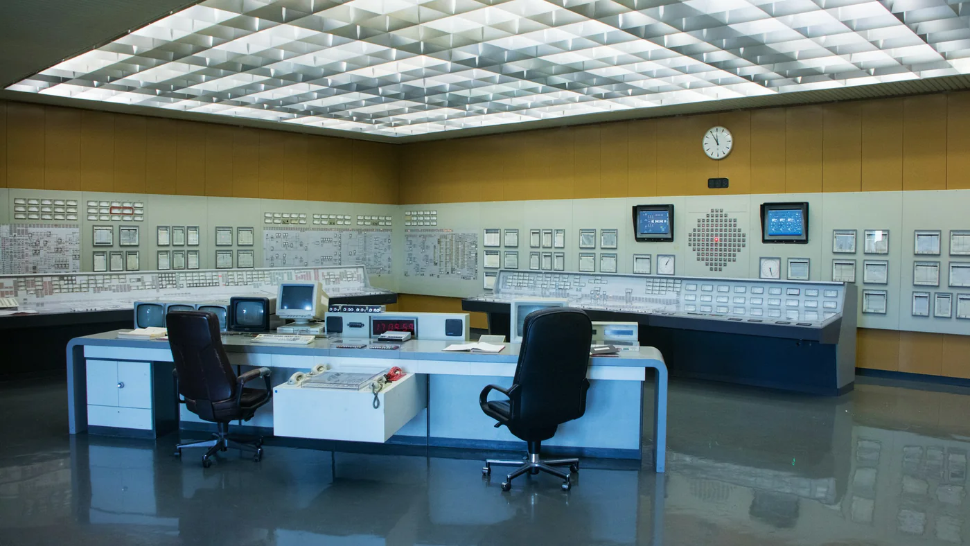 Ruime controlekamer met bureaus en schakelpanelen
