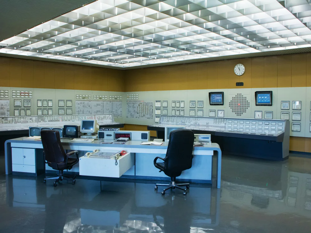 Ruime controlekamer met bureaus en schakelpanelen