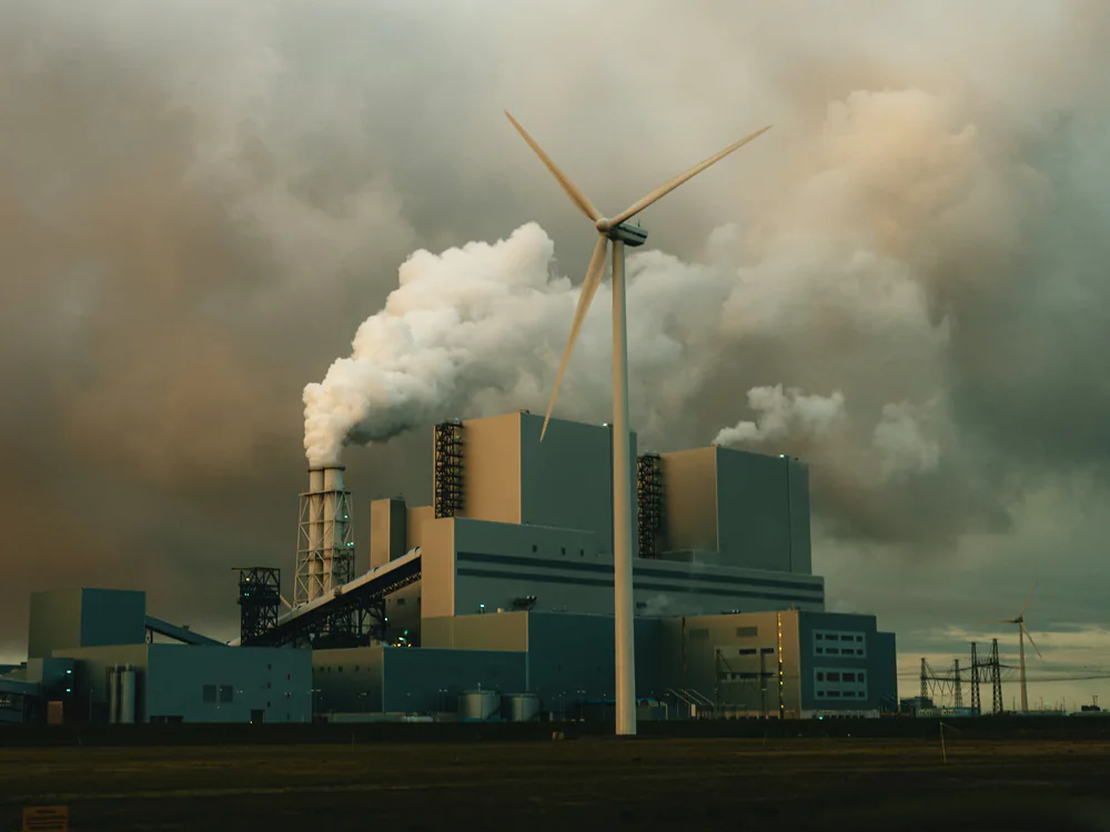 Centrale met rookpluim en windturbine bij de Eemshaven