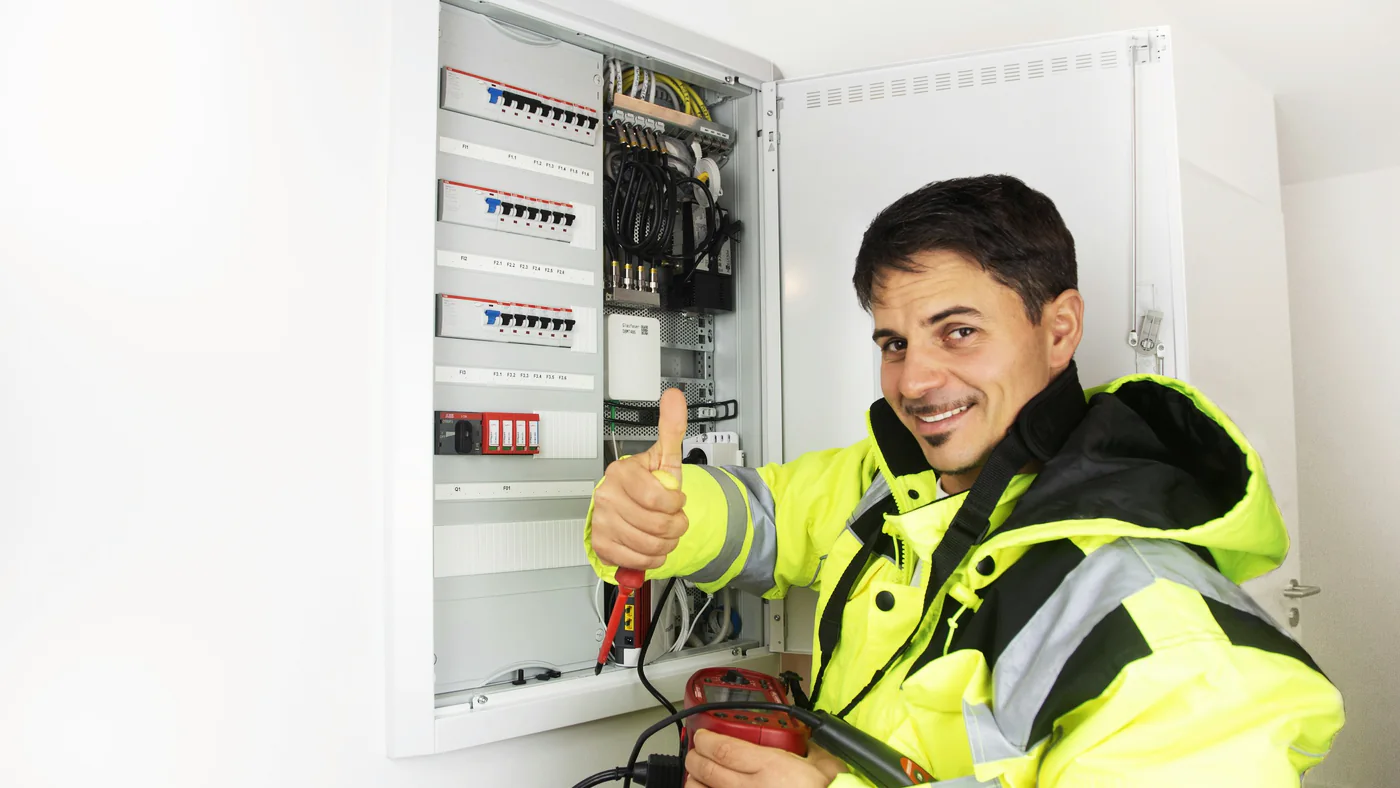 Elektromonteur in signaalkleding bij een geopende meterkast
