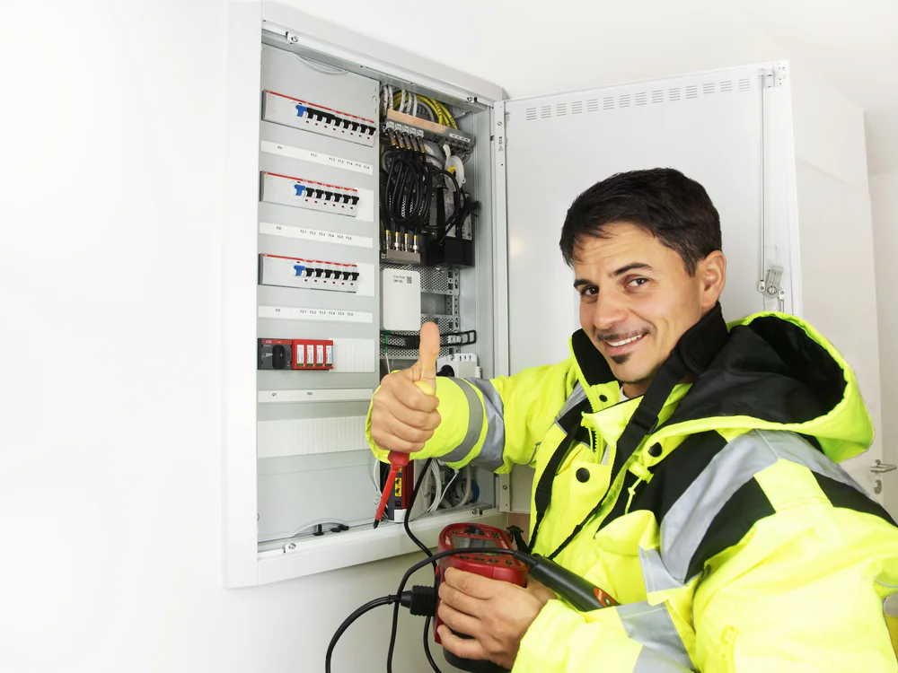 Elektromonteur in signaalkleding bij een geopende meterkast