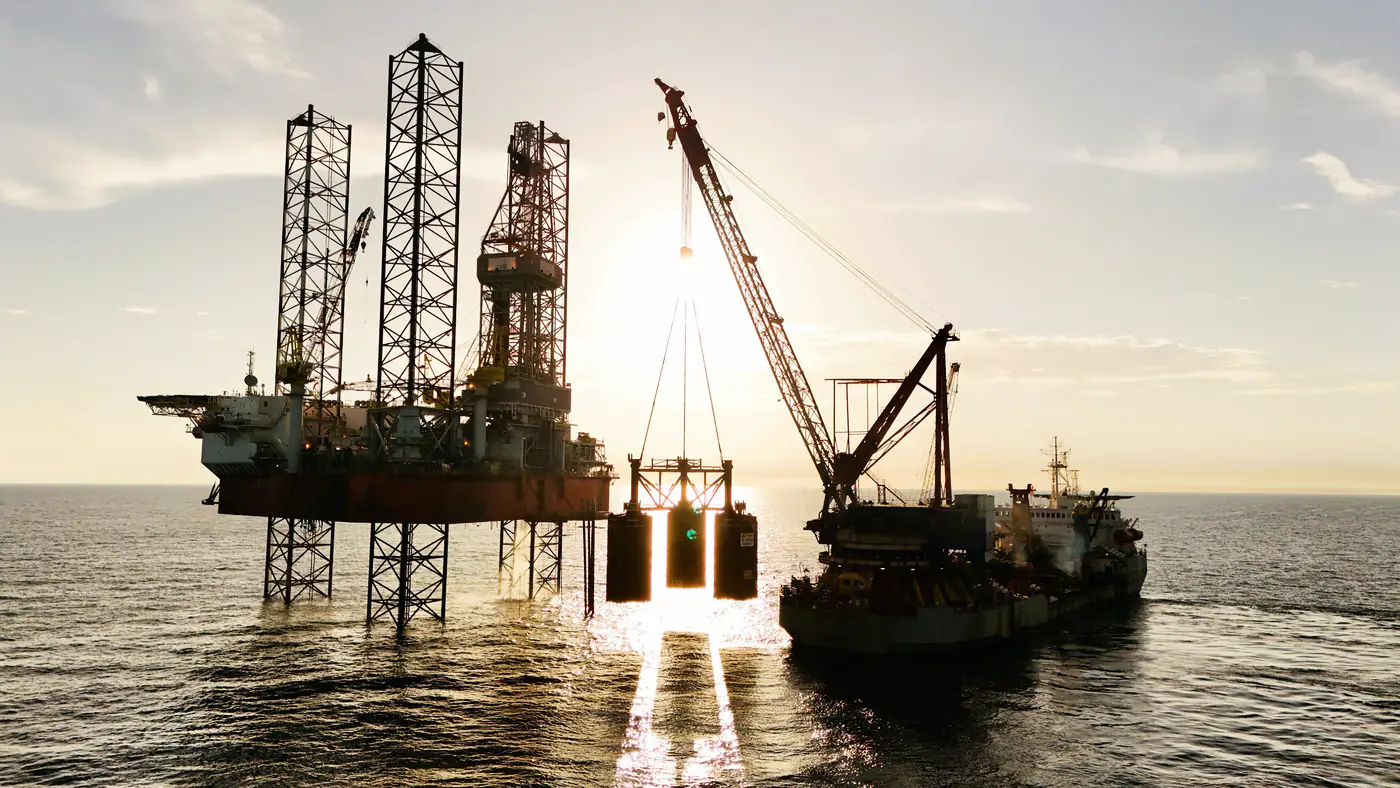 Hefplatform en kraanschip op zee bij zonsondergang