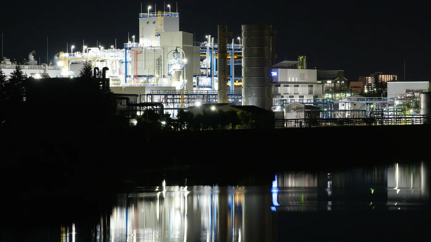 Industrieterrein bij nacht met reflectie in het water
