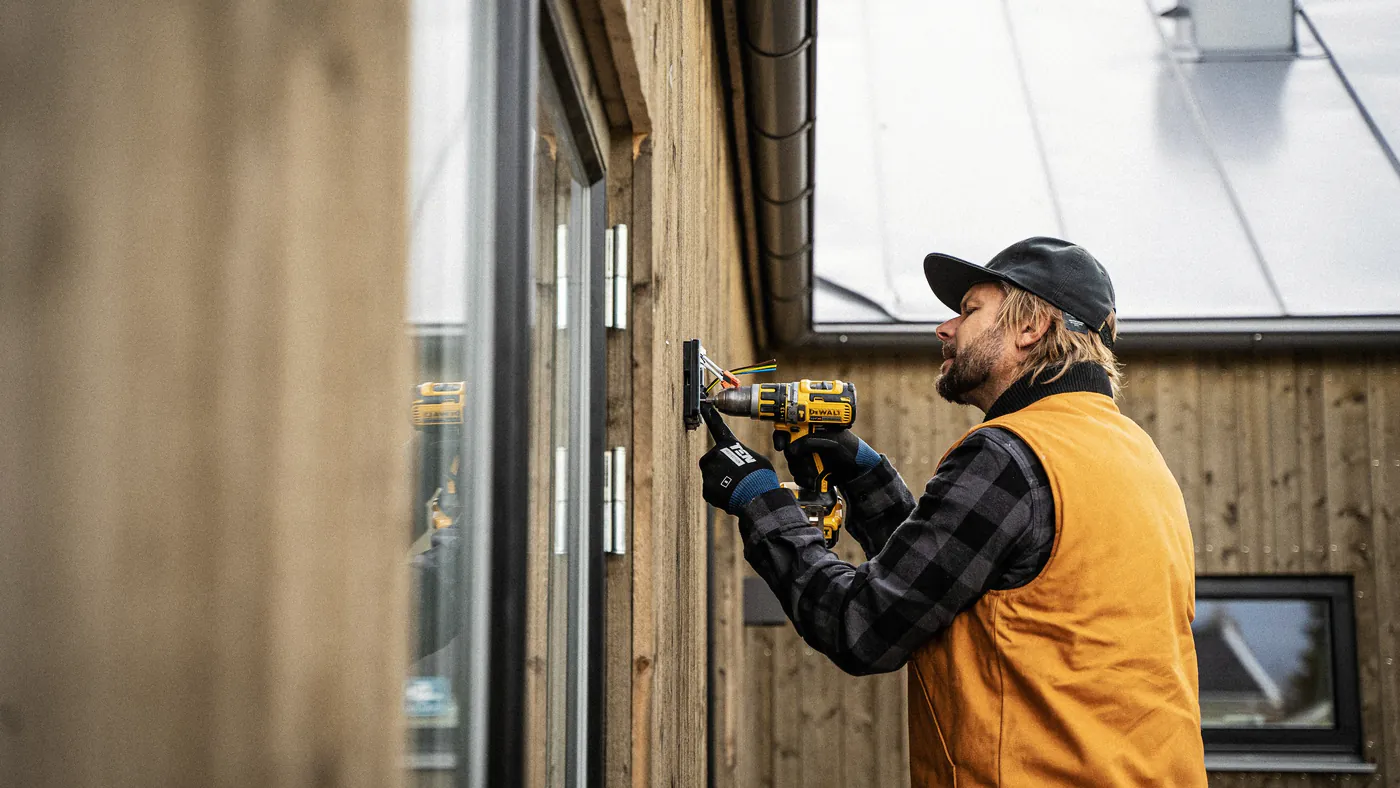 Installateur boort een gat in een houten gevel