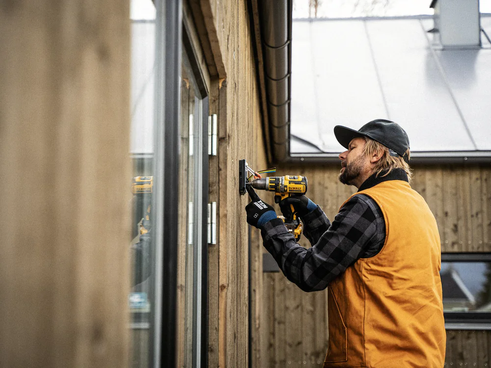 Installateur boort een gat in een houten gevel