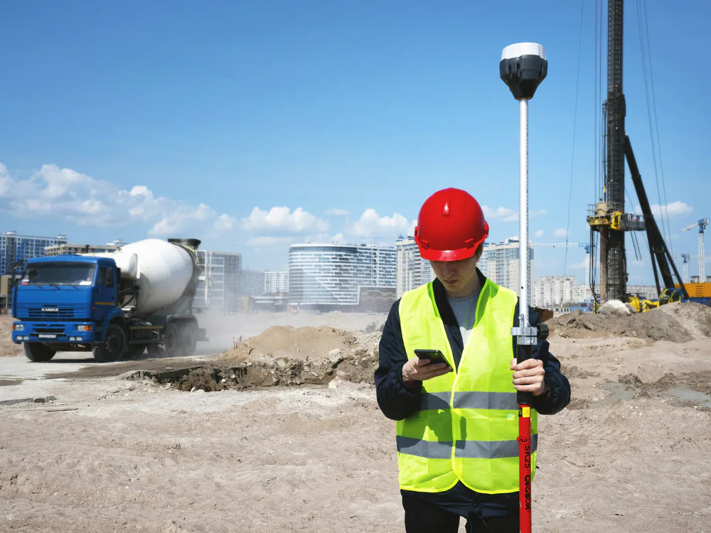 Maatvoerder met helm en meetstok op een bouwterrein