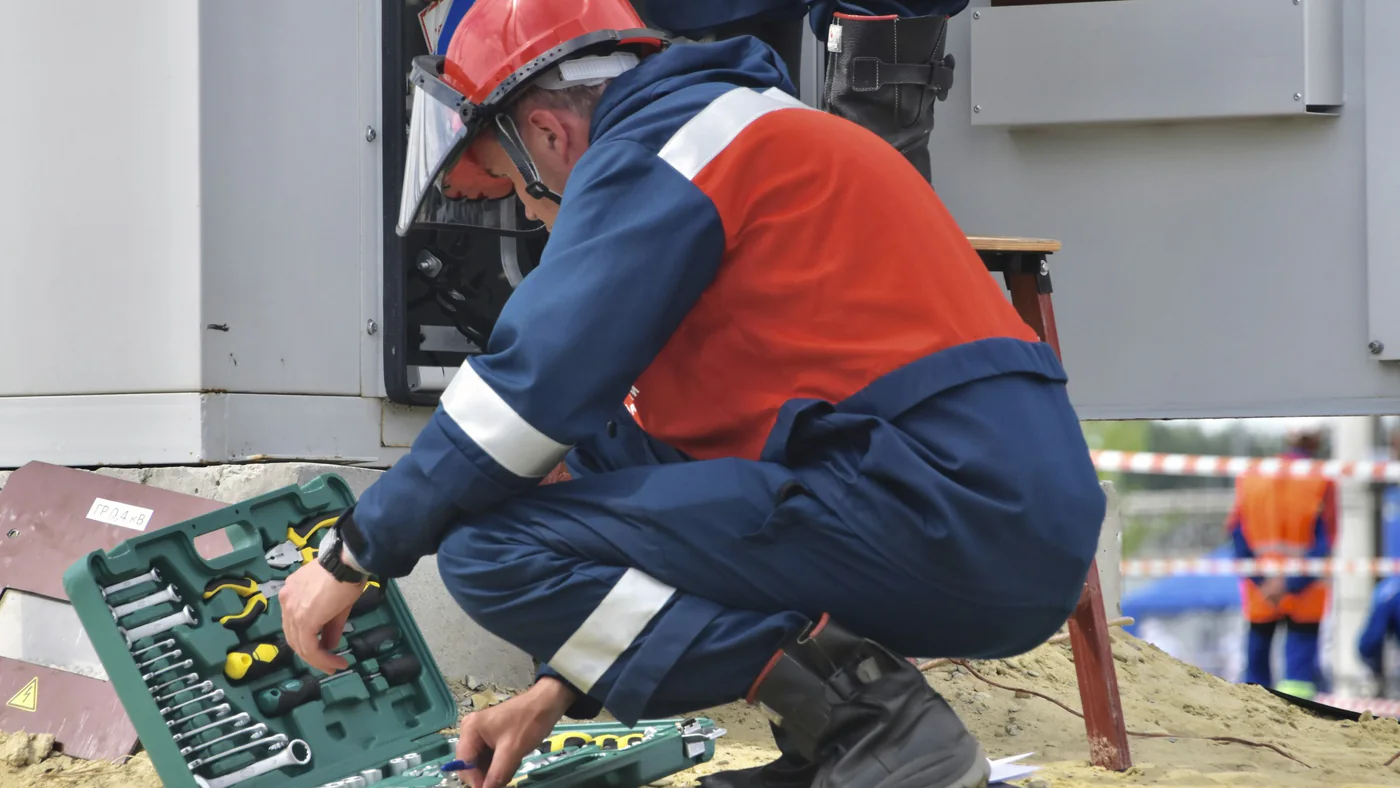 Monteur met helm pakt gereedschap uit een koffer
