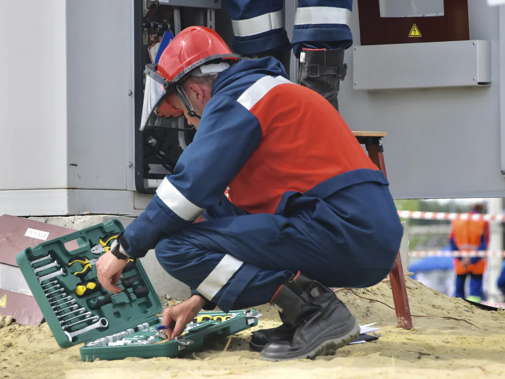Monteur met helm pakt gereedschap uit een koffer