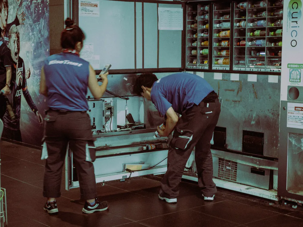Twee monteurs werken samen aan een machine in een hal