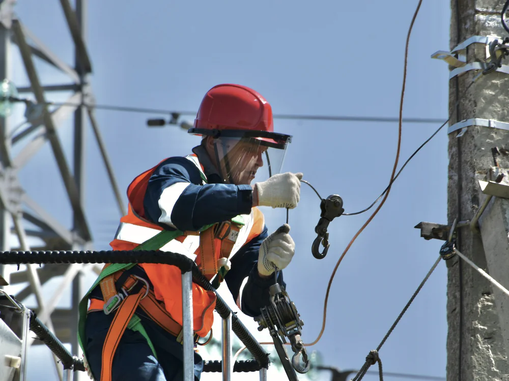 Netmonteur met helm en harnas werkt aan een bovengrondse verbinding