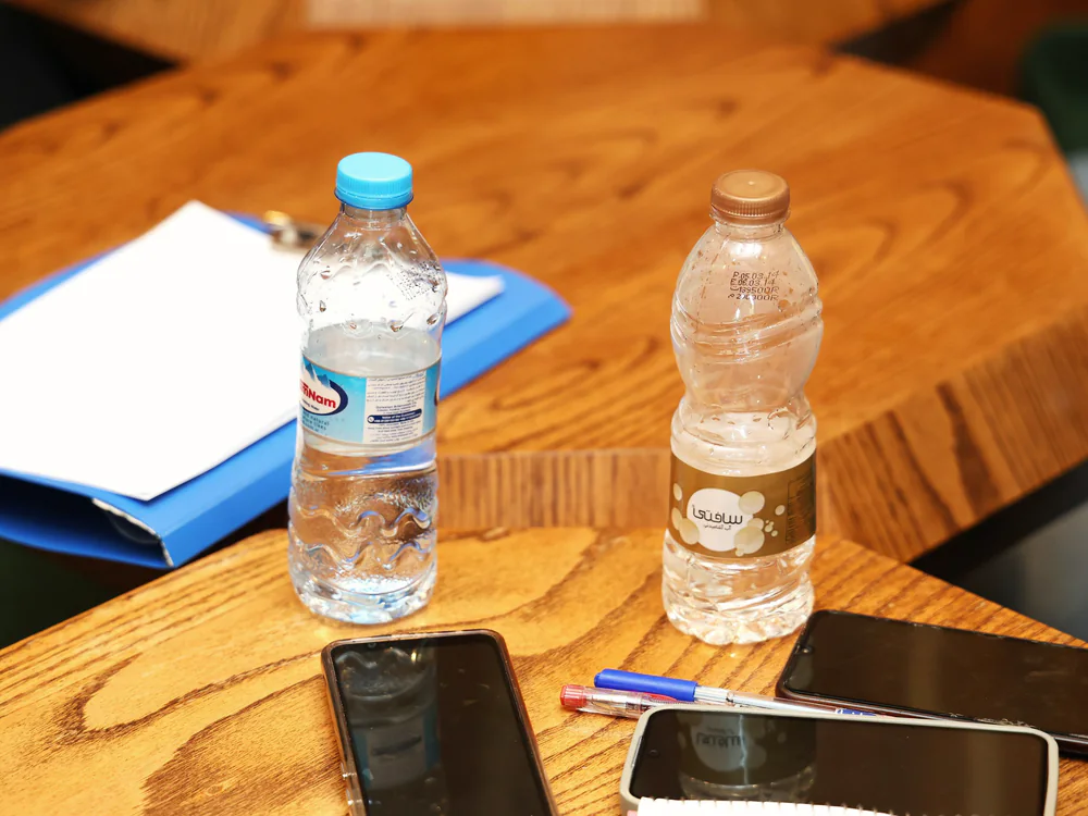 Ordners, telefoon en waterflesjes op een houten bureau