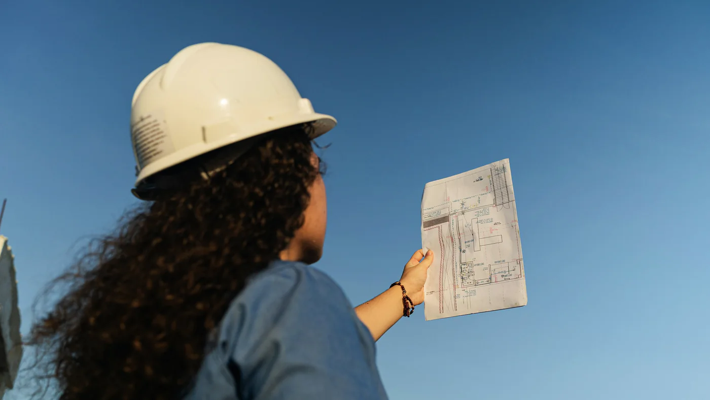 Projectleider met helm bekijkt een bouwtekening