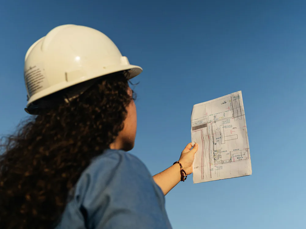 Projectleider met helm bekijkt een bouwtekening