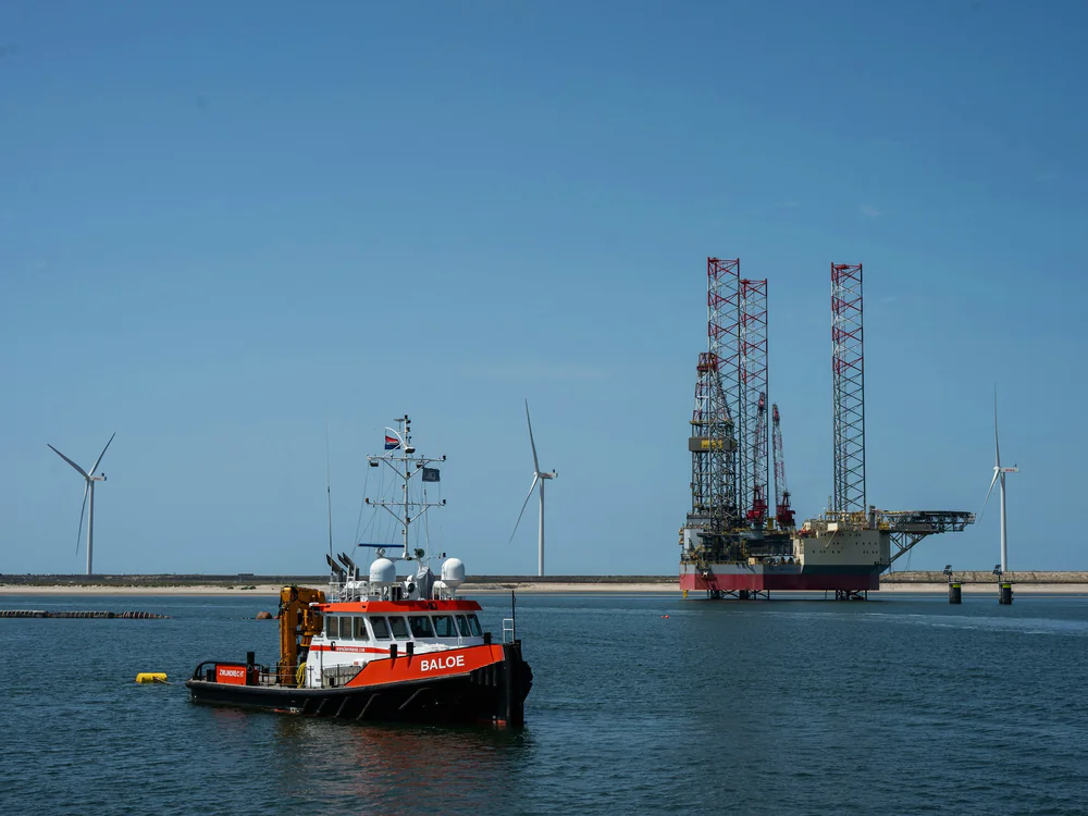 Sleepboot en hefplatform in de haven, windturbines op de achtergrond