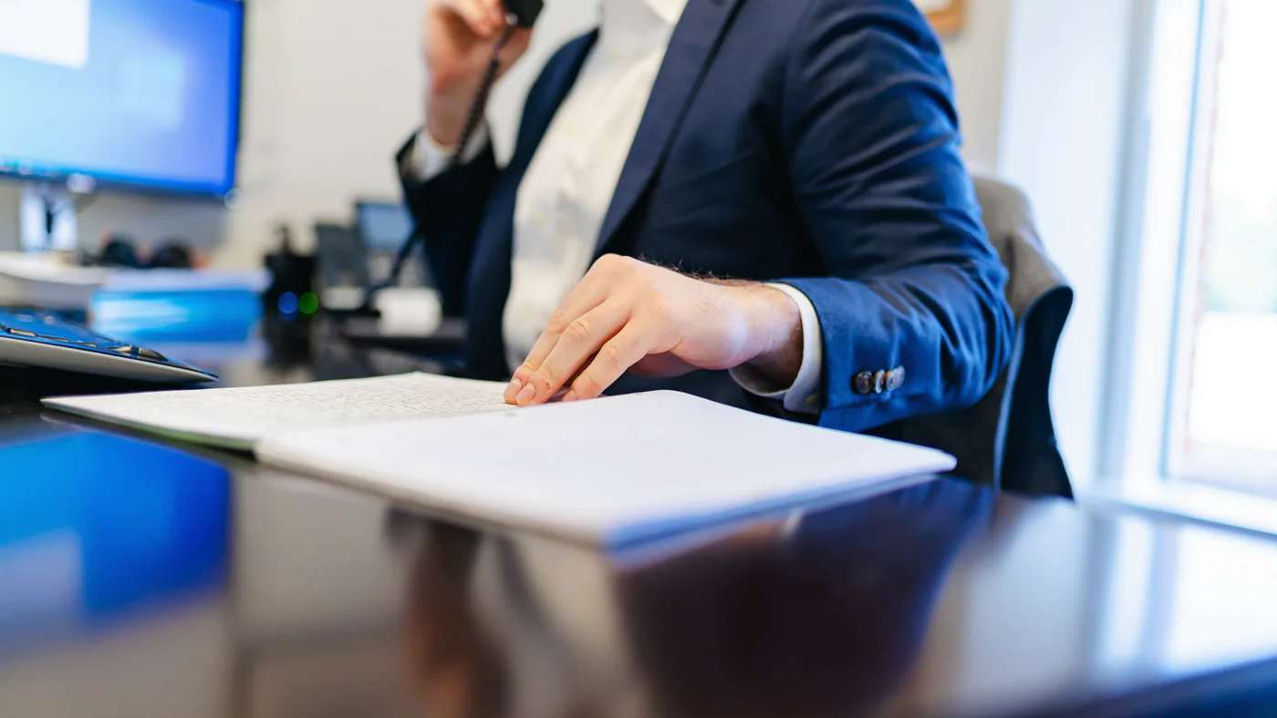 Man belt aan een bureau met documenten