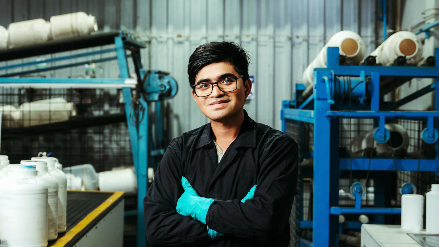 Jonge vakman met bril en handschoenen in een productiehal