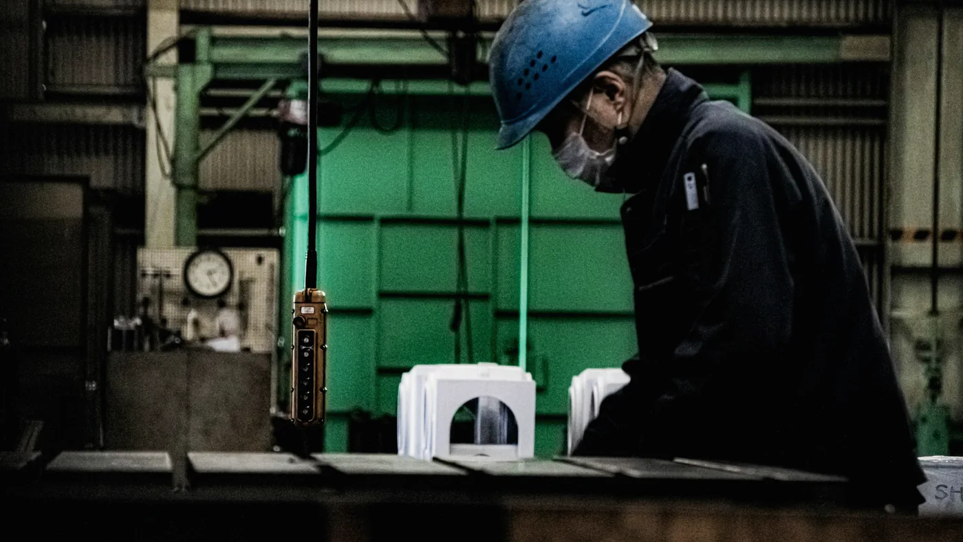 Vakman met helm aan het werk in een fabriekshal