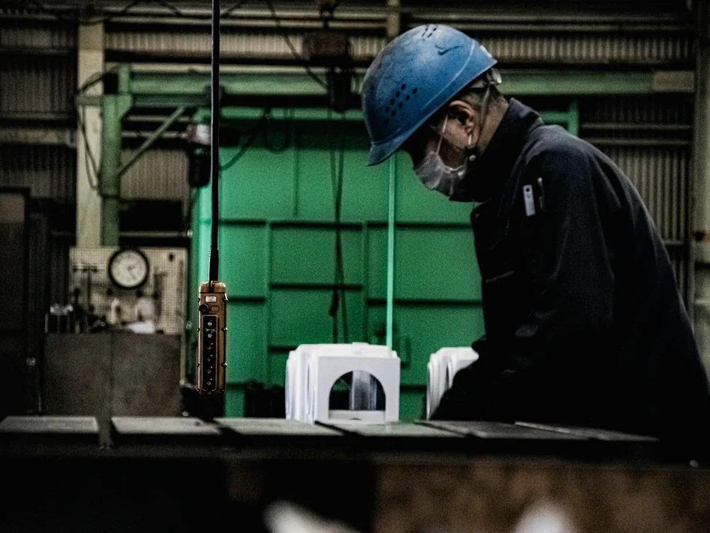 Vakman met helm aan het werk in een fabriekshal