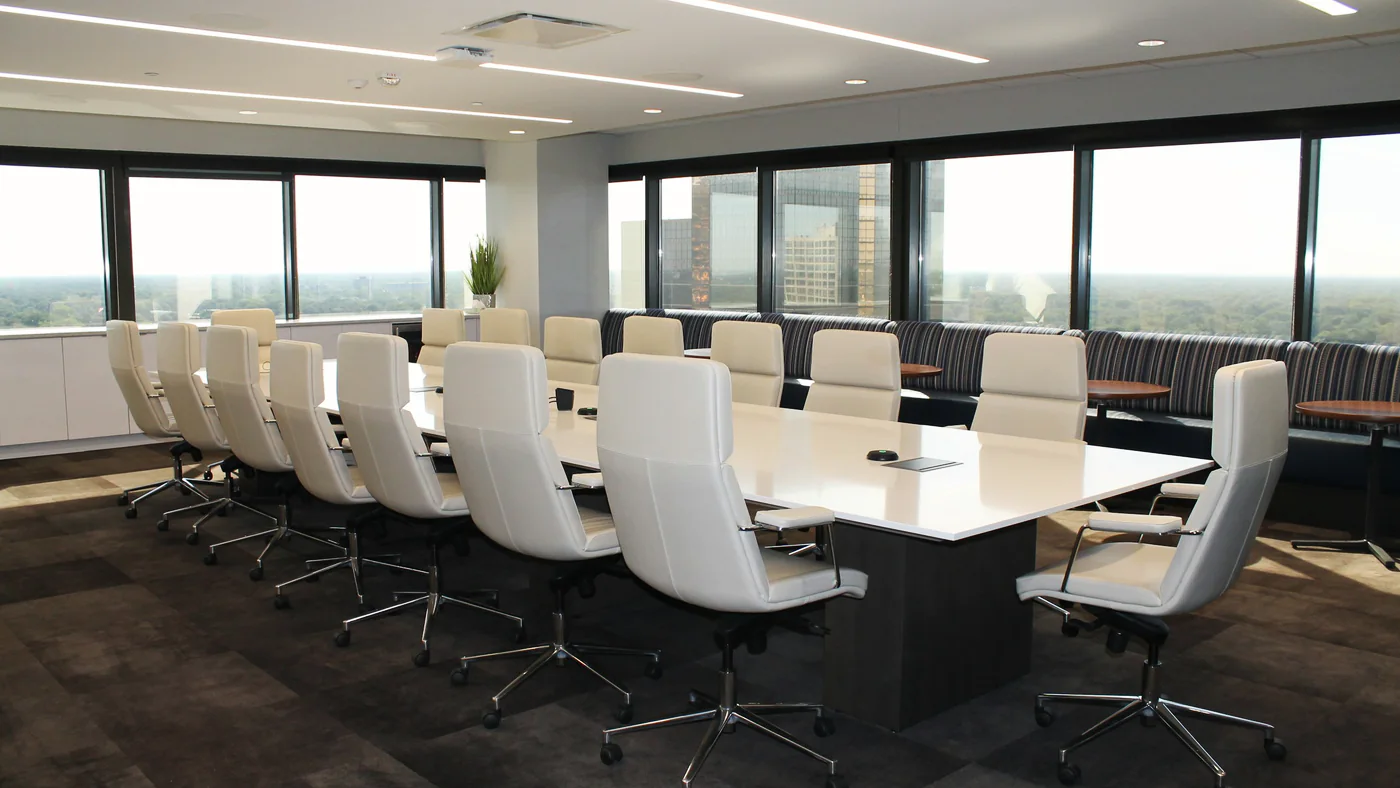 Lichte vergaderzaal met een lange tafel en witte stoelen