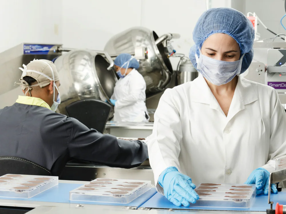 Medewerker in hygienekleding werkt met producten aan een rvs-tafel
