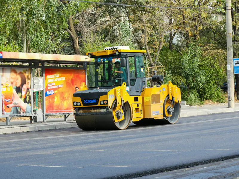Wals werkt aan een nieuwe asfaltlaag langs een bushalte