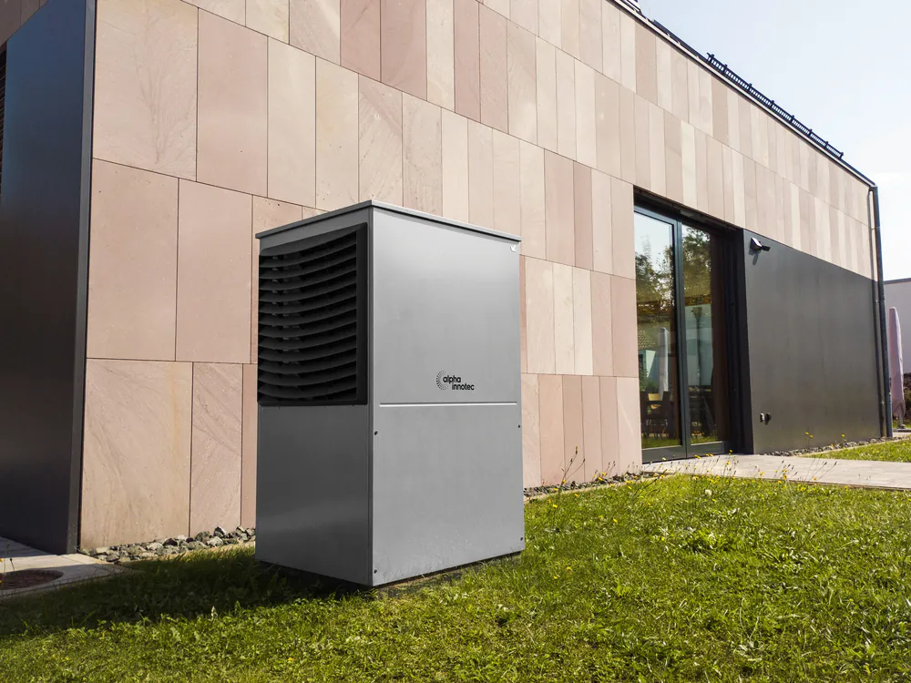 Warmtepomp op het gras naast een modern bedrijfspand
