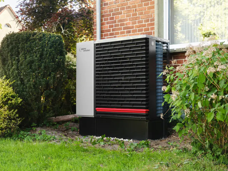 Warmtepomp in de tuin van een woning met bakstenen gevel