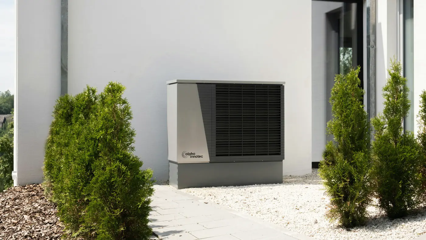 Buitenunit van een lucht-waterwarmtepomp naast een moderne woning