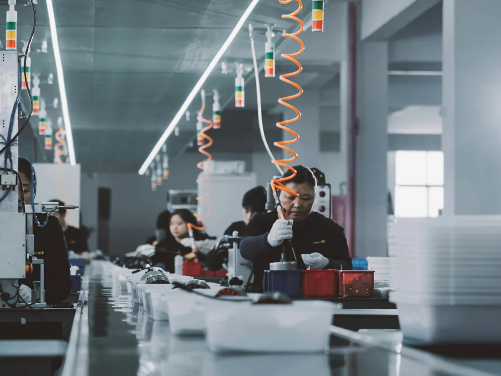 Medewerkers aan een werkstation in een productiehal