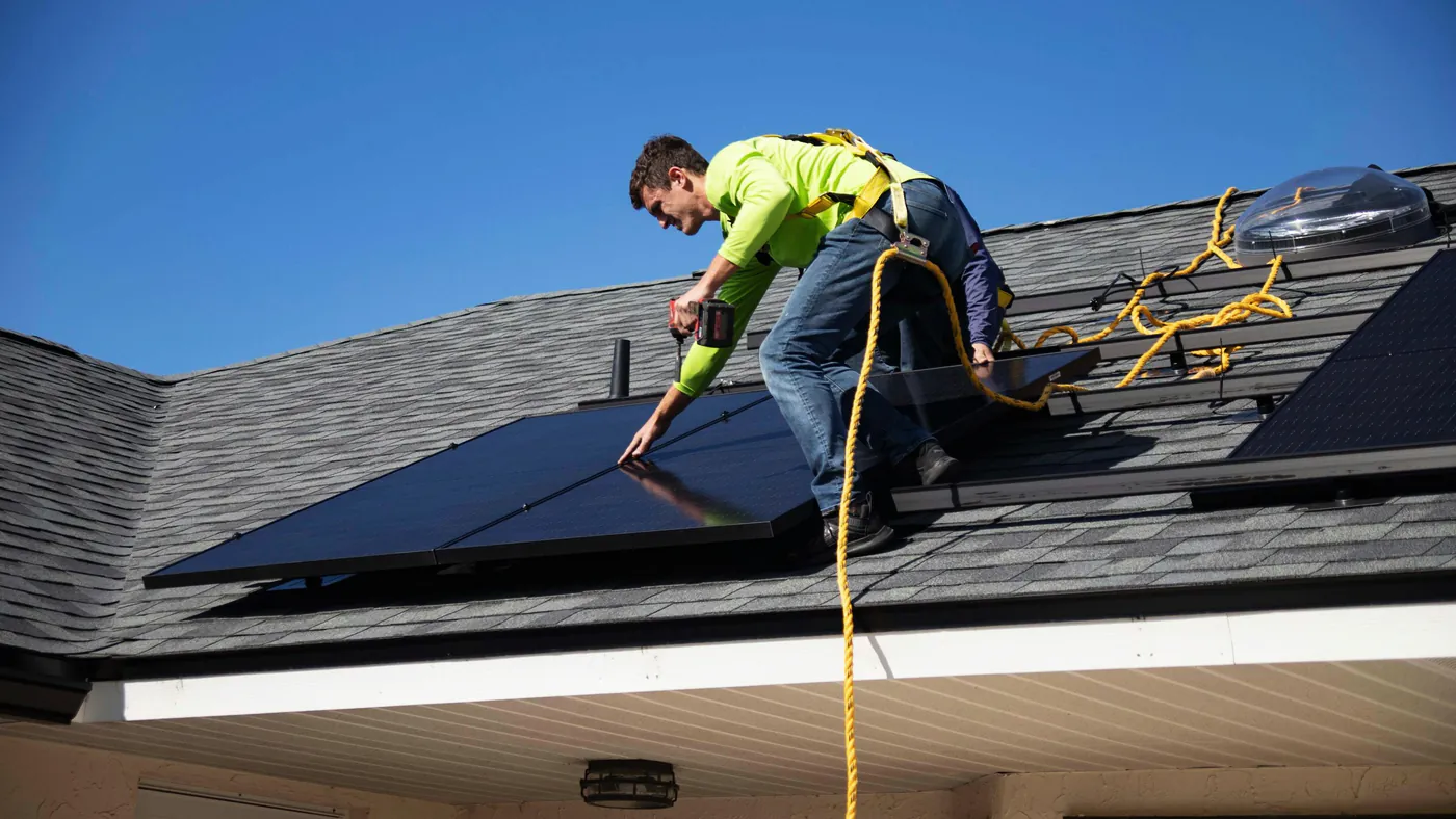 Monteur met valbeveiliging legt zonnepanelen op een dak