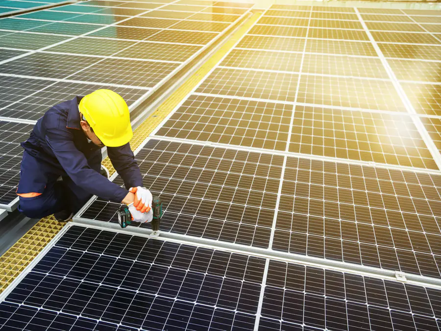 Monteur met veiligheidshelm werkt aan een veld met zonnepanelen
